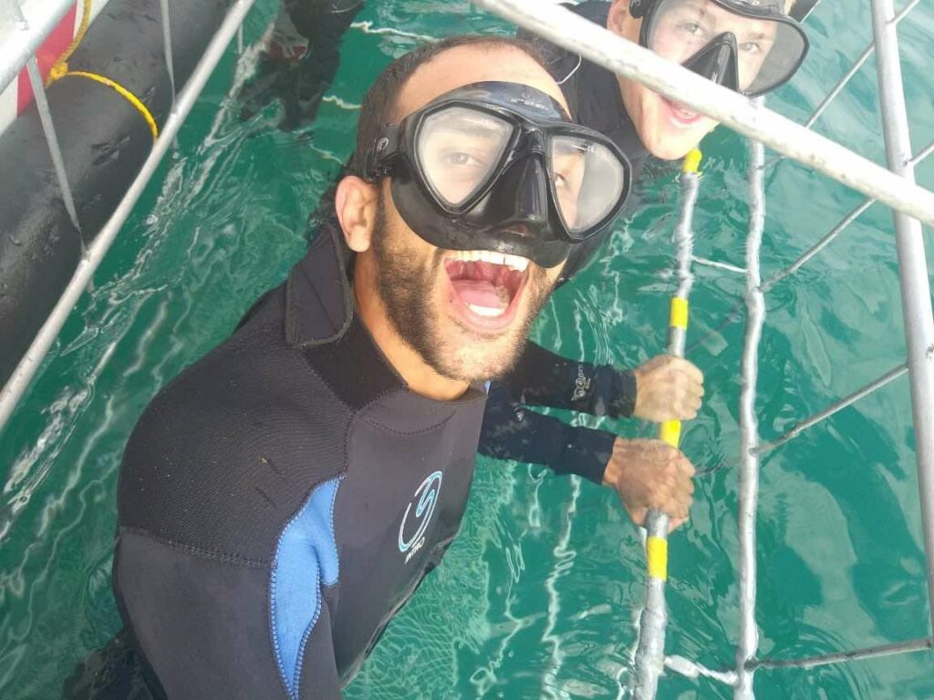 diver with mask on in shark cage smiling